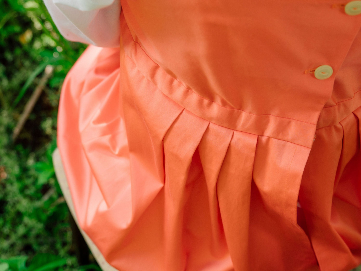 A close-up shows pleats in the back skirt of a salmon-colored Regency petticoat