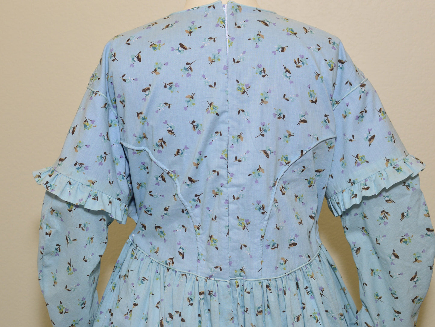 A photo of the back of a blue floral fan dress shows piping in the princess seams in the back bodice