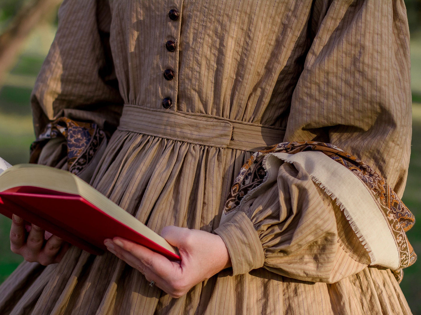 A close-up photo of a brown 1860s dress shows piping on the waistband
