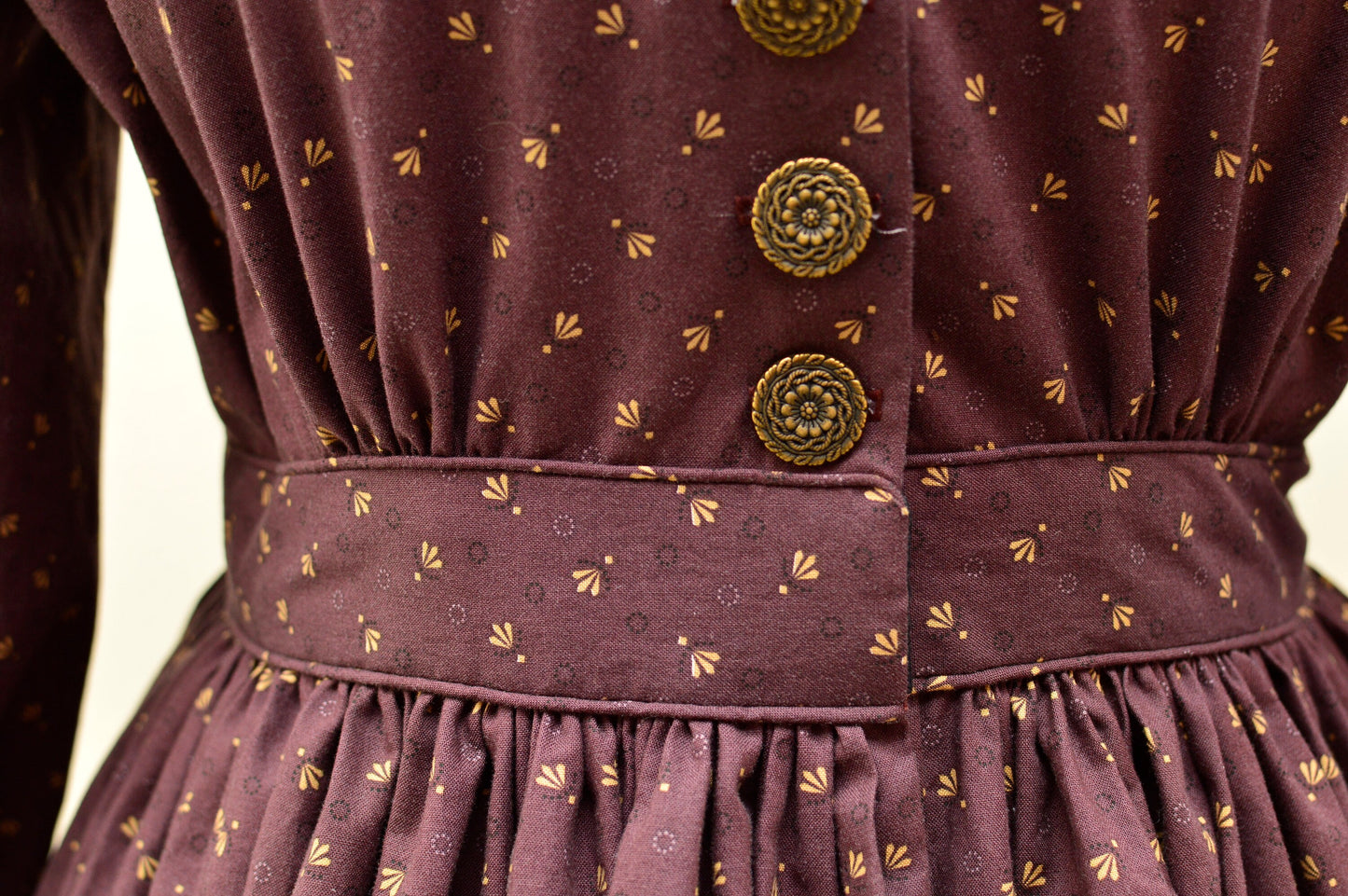 A close-up shows piping on the waistband of a purple floral Victorian dress