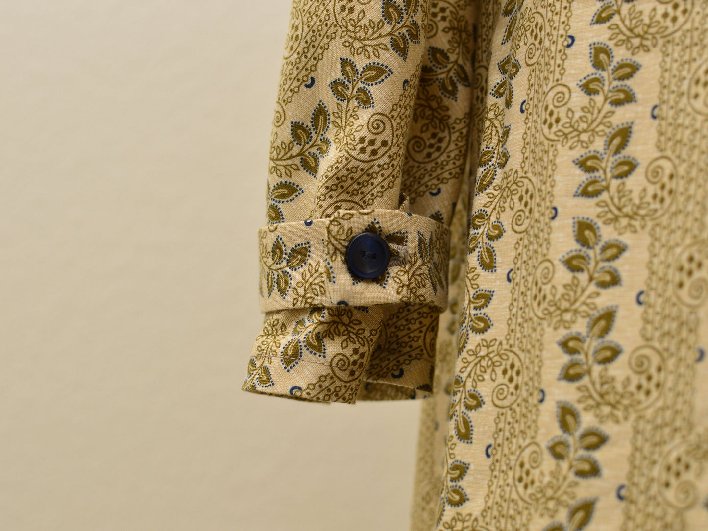 A close-up shows the sleeve detail on a tan floral Regency gown: a matching band buttons around the wrist.