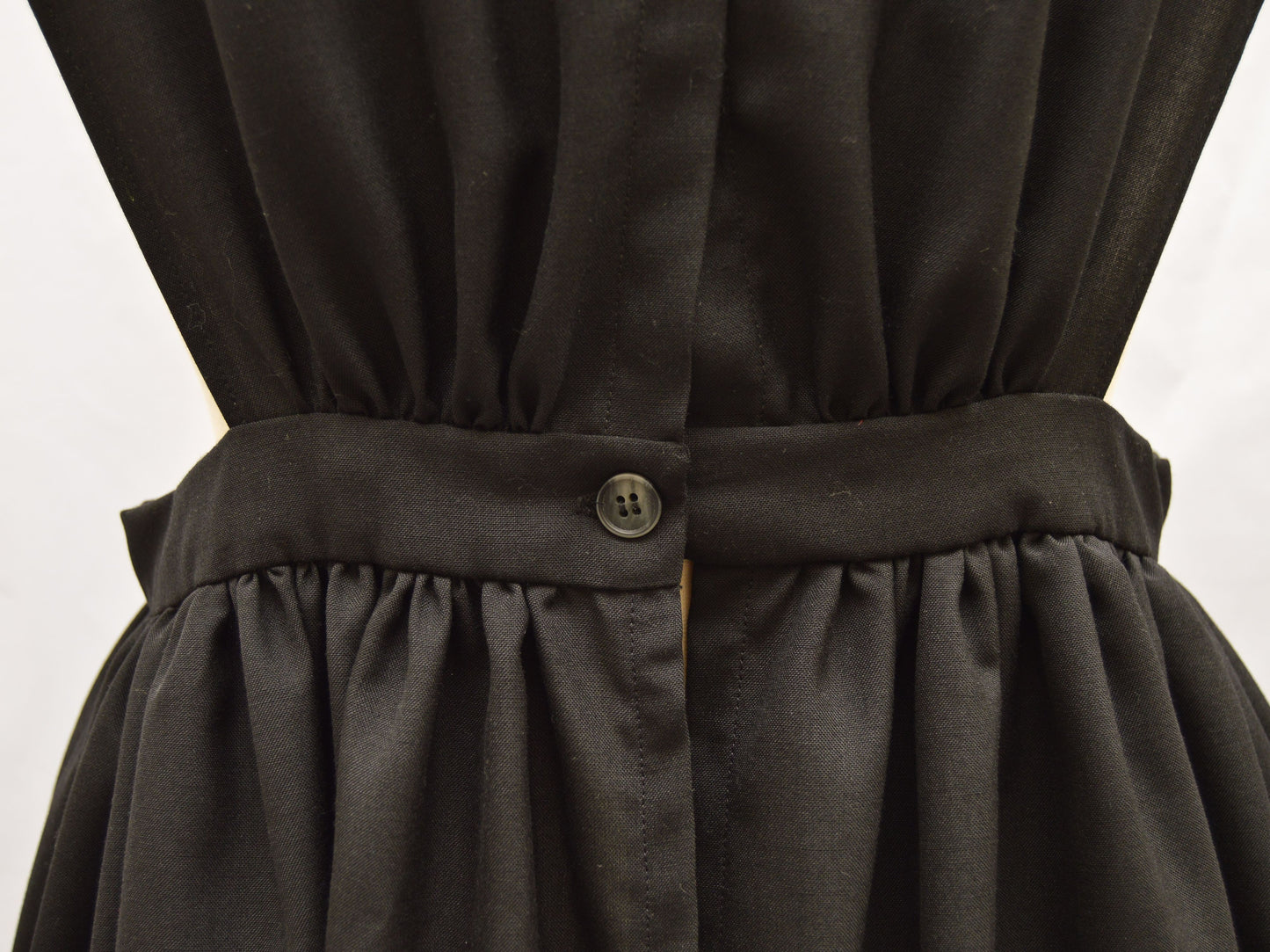 A close-up back view of an 1860s wool pinafore waistband with button closure