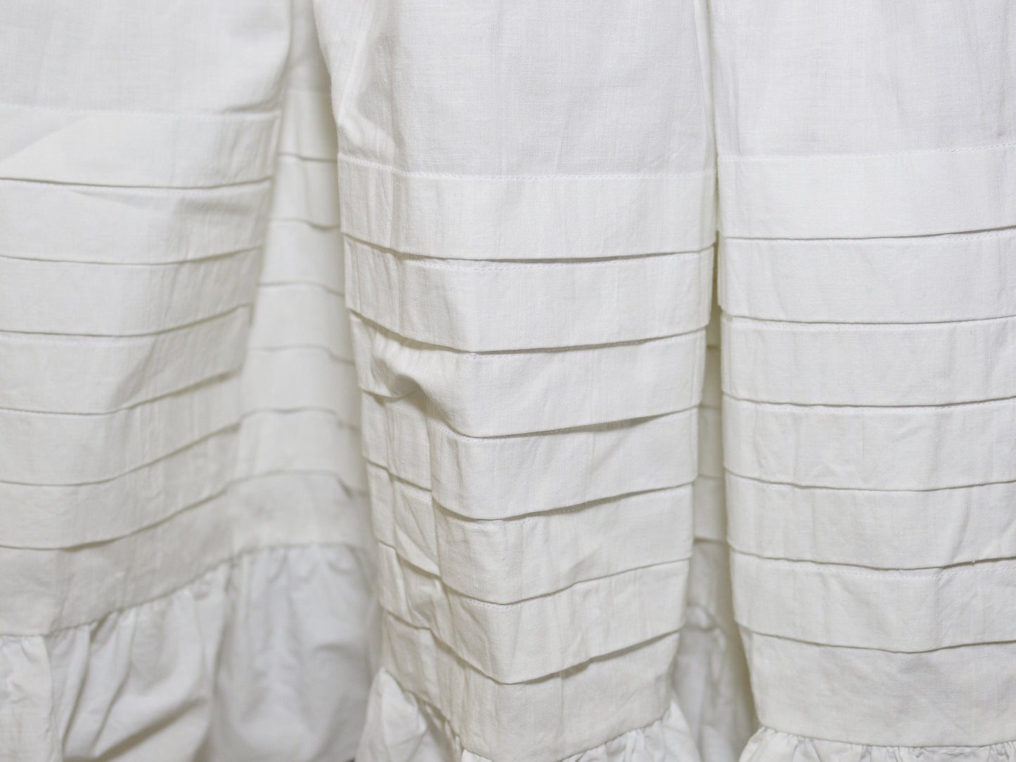 A close-up shows the six deep tucks on the hem of a Victorian petticoat