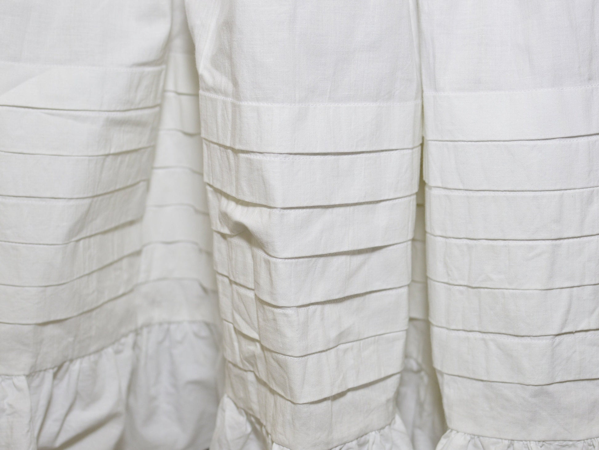 A close-up shows the six deep tucks on the hem of a Victorian petticoat