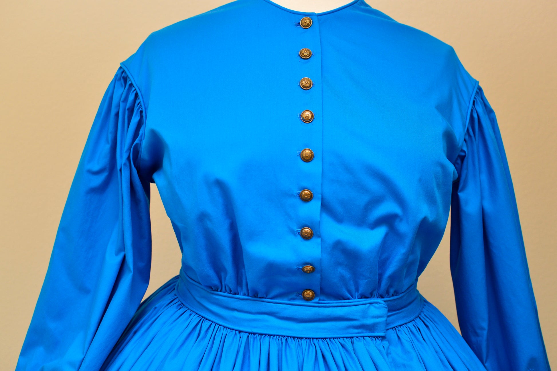 A photo of an 1860s dress on a dress form, showing the dog-leg closure